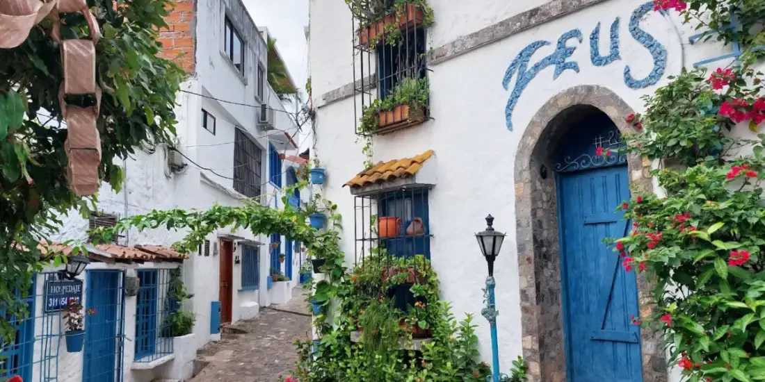 Calles blancas empedradas y puertas azules en el pintoresco barrio La Aldea, conocido como el Santorini Colombiano en Doradal, Antioquia.